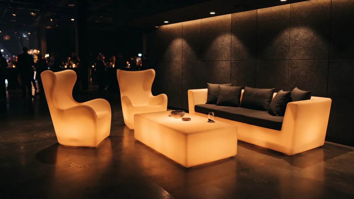 Világító LED kanapé, két magas háttámlás fotel és egy nagy világító asztal egy céges lounge sarokban